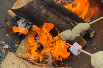 Stecken mit Stockbrot und Marshmallow &uuml;ber einem Lagerfeuer