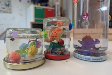 Von Kindern gebastelte Schnelkugeln mit bunten Dinosaurier-Figuren