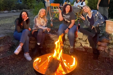 Vier junge Frauen sitzen um eine Feuerschale im Hof des Don Bosco Jugendwerks N&uuml;rnberg