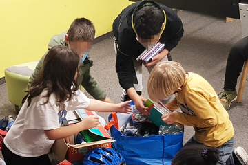 Kinder packen die Sachspenden der Firma PPD Germany an das Don Bosco Jugendwerk Nürnberg aus